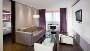 a living room with a couch and a television in a room at Meliá Lebreros in Seville