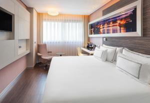 a hotel room with a large white bed and a desk at Meliá Lebreros in Seville