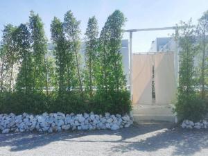 a fence with trees in front of a building at 7 Class Pool Villa in Chachoengsao