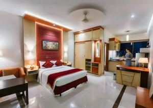 a hotel room with a bed and a woman in a kitchen at Green Goose by Lakeshore Dhaka in Dhaka