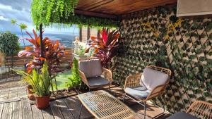a patio with two chairs and a table and some plants at VACANCES PAISIBLES - Option Menu & petit-déjeuners payant in Saint-Paul