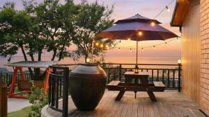 a patio with a table and an umbrella and a bench at Yeosu Hwangto Pension in Yeosu