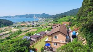 a house on a hill next to the water at Yeosu Hwangto Pension in Yeosu
