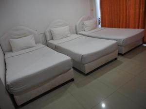 two beds and a couch in a room at Phetsuwan Hotel in Phetchabun