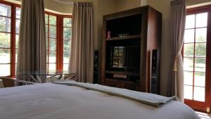 a bedroom with a bed and a tv and windows at Tuckaway in Somerset West