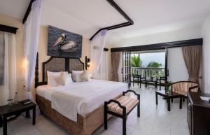a bedroom with a large bed and a balcony at PrideInn Flamingo Beach Resort & Spa Mombasa in Mombasa