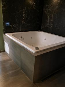 a bath tub in a bathroom with a black wall at Hotel Castelar suit in Castelar