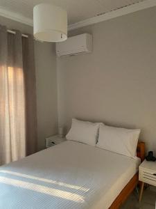 a bedroom with a large white bed with a window at Betty's Seaside Olive House in Ofrínion