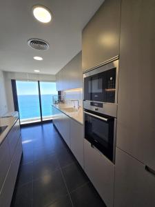 a kitchen with stainless steel appliances and a view of the ocean at Beachfront with pool and great views in Mataró