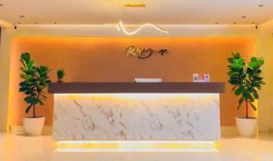 a lobby with a marble counter with two potted plants at Rhyme Hotel - Hitech City in Hyderabad