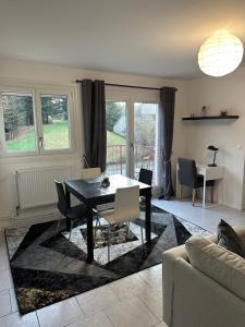 a living room with a black table and chairs at Les Jonchères - appartement cosy proche Thermes in Luxeuil-les-Bains