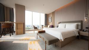 a hotel room with a large bed and a desk at Elong Hotel Jakarta PIK in Jakarta