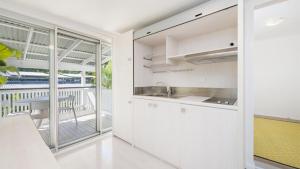 a kitchen with white cabinets and a balcony at Whalesong in New Brighton