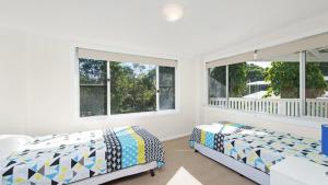 two beds in a bedroom with two windows at Whalesong in New Brighton +7 photos