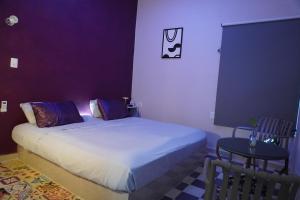a small bedroom with a bed and a table at Pequeño Refugio in Ticul