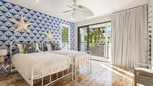 two beds in a bedroom with blue and white wallpaper at The Anchorage in New Brighton