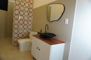 a bathroom with a sink and a toilet and a mirror at Pequeño Refugio in Ticul