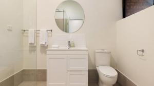 a white bathroom with a toilet and a mirror at Brunswick Palms 1 in Brunswick Heads +6 photos
