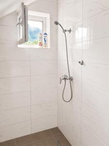 a white bathroom with a shower with a window at Guest House Ulnika in Vusanje +24 photos