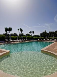a large swimming pool with lounge chairs and water at My Place modern living in Kefalos