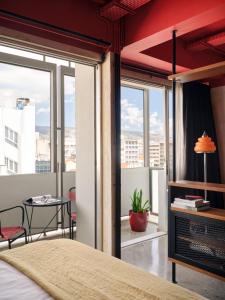a bedroom with a bed and a balcony with a table at Max Brown Hotel Downtown Part of Sircle Collection Formally known as Dave Red in Athens