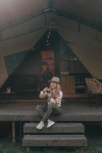 a woman sitting on a bench holding a camera at Liva Park Nature Resort in Liwa