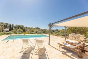 a villa with a swimming pool and two chairs at Trulli Oasis in Noci