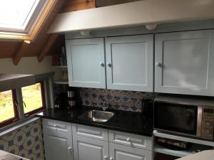 a kitchen with white cabinets and a sink at Boerderijte De Lytse Formerum in Formerum +3 photos