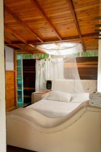 a bedroom with a white bed with a wooden ceiling at Villas del Rio Glamping in San Francisco