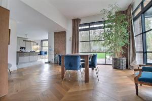 a dining room with a table and blue chairs at Villa golf merignies in Mérignies