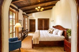 a bedroom with a bed and a blue chair at Nifu nifa in Antigua Guatemala