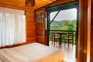 a bedroom with a bed and a balcony with a table at Villas del Rio Glamping in San Francisco