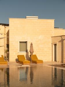 a pool with yellow chairs and an umbrella at Dimora Mennuti in Monteparano