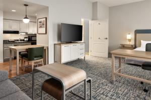 a living room with a couch and a table with a television at Homewood Suites New Brighton in Roseville