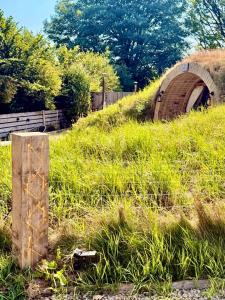 a wooden post in a grassy field with a bridge at Nook in Binegar