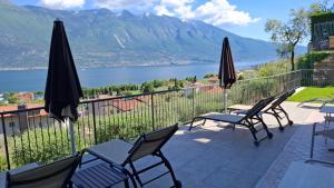 a patio with chairs and umbrellas overlooking a lake at Villa Imelda, panoramic apartments with Lake Garda views in Limone sul Garda