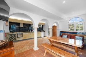 a living room with a wooden table and a kitchen at Quinta da Paz in Caniço