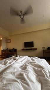 a bedroom with a white bed with a ceiling fan at Jj Internatinals Group in Bhopal