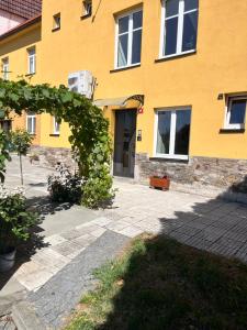 a yellow building with an arch in front of it at Apartmány RK in Horažďovice