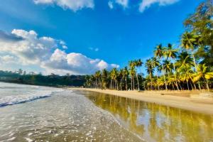 a beach with palm trees and the ocean at The Mangrove Cove "200Mtrs from Beach" in Shādipur