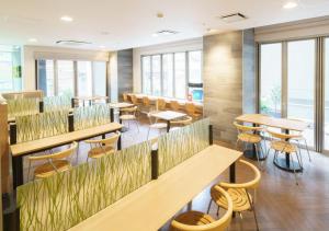 a restaurant with tables and chairs and windows at Super Hotel Midosujisen Esaka in Suita
