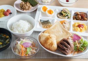 a table with plates of food and bowls of food at Super Hotel Midosujisen Esaka in Suita