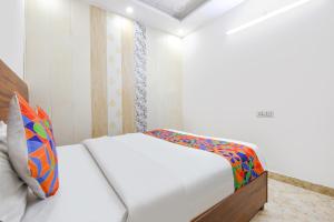 a small bedroom with a white bed with a colorful pillow at FabHotel Lotus Star in New Delhi