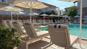 a row of chairs and umbrellas next to a pool at The Mathraki Studios in Arillas
