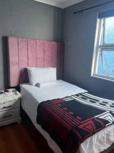 a small bedroom with a bed and a window at Vee's Cottage in Bellville