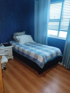 a blue bedroom with a bed and a window at Vee's Cottage in Bellville +1 photo