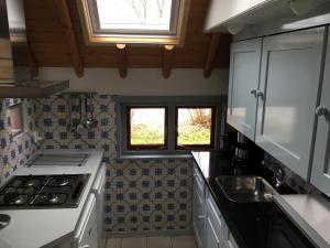 a kitchen with a stove and a sink and two windows at Boerderijte De Lytse Formerum in Formerum