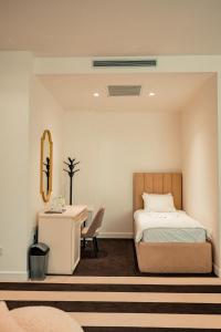 a bedroom with a bed and a desk with a chair at HOTEL BALKAN in Bijeljina