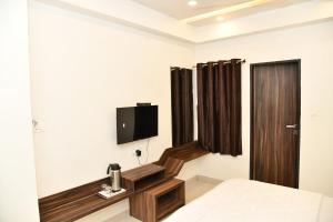 a bedroom with a bed and a tv on the wall at Hotel Shreeji Palace in Ābu Road +13 photos