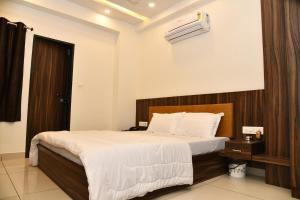 a bedroom with a large bed with a wooden headboard at Hotel Shreeji Palace in Ābu Road